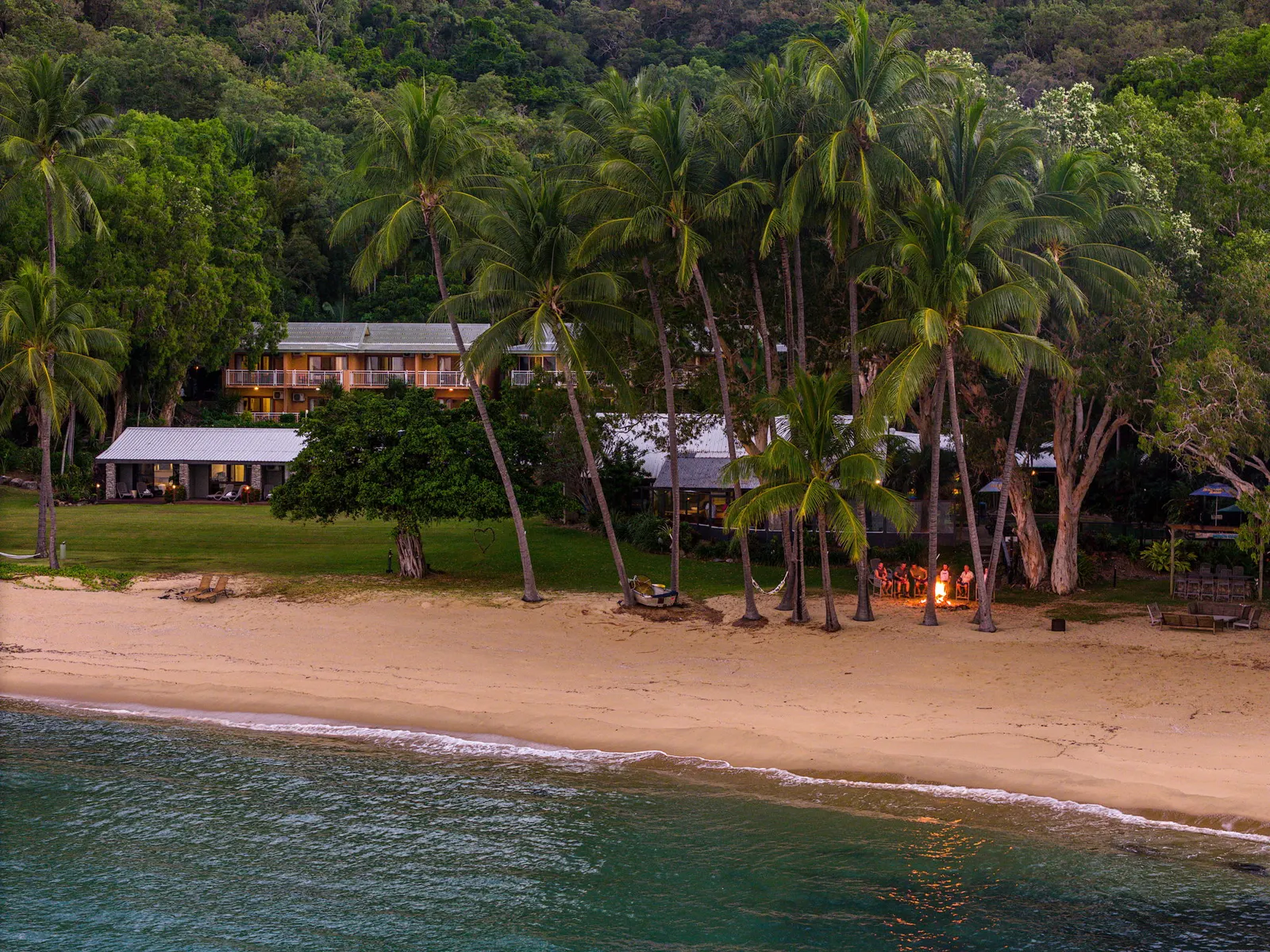 The resort seen from the water, behind the beach and palms
