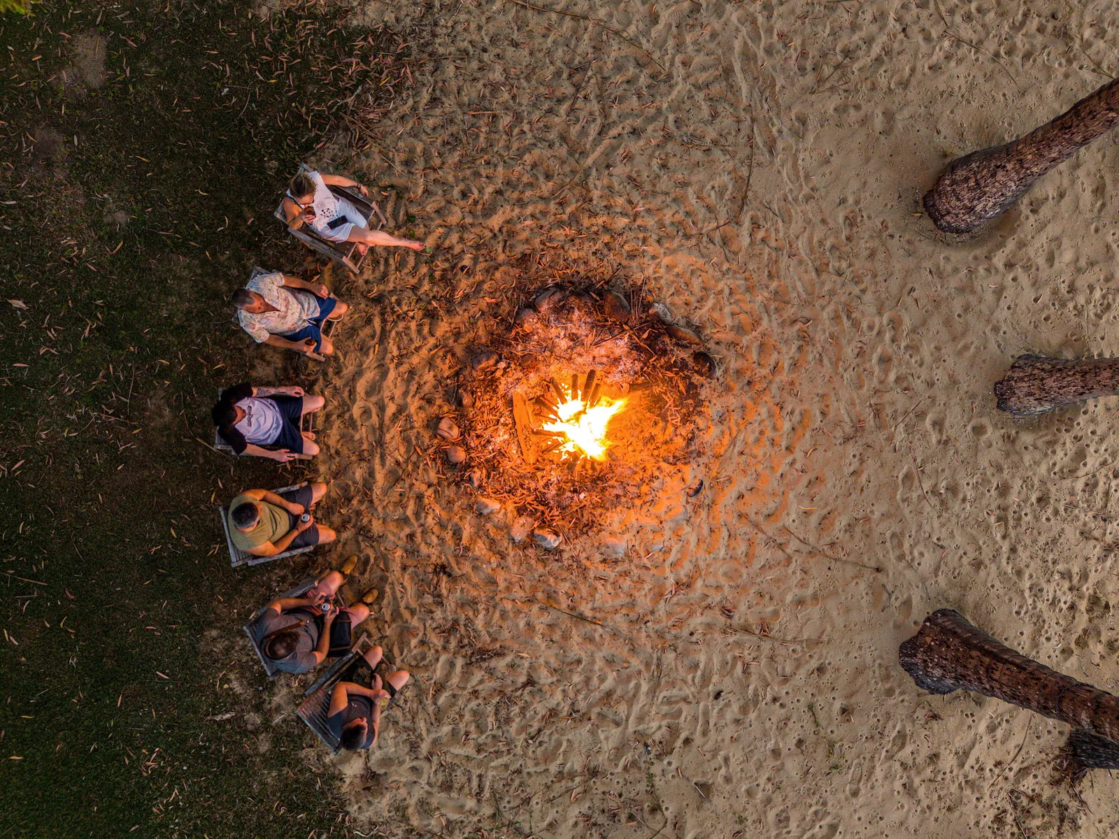 Guests around a fire on the beach at night, seen from above