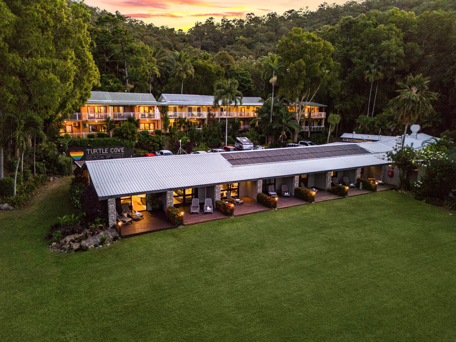 Resort accommodation wing lit at dusk with lawn in front
